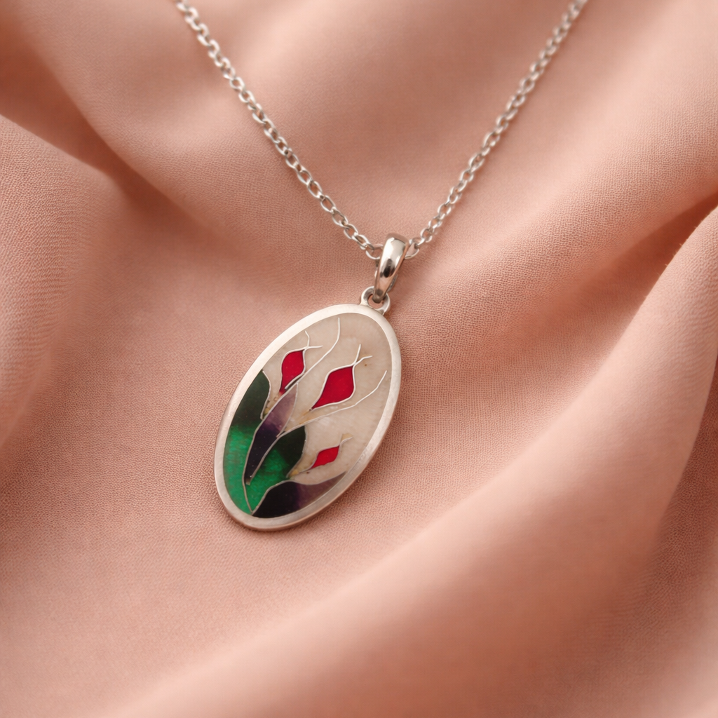 Silver necklace with a floral pendant on a pink fabric background