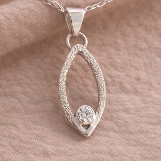 Silver pendant with a round gemstone on a beige fabric background