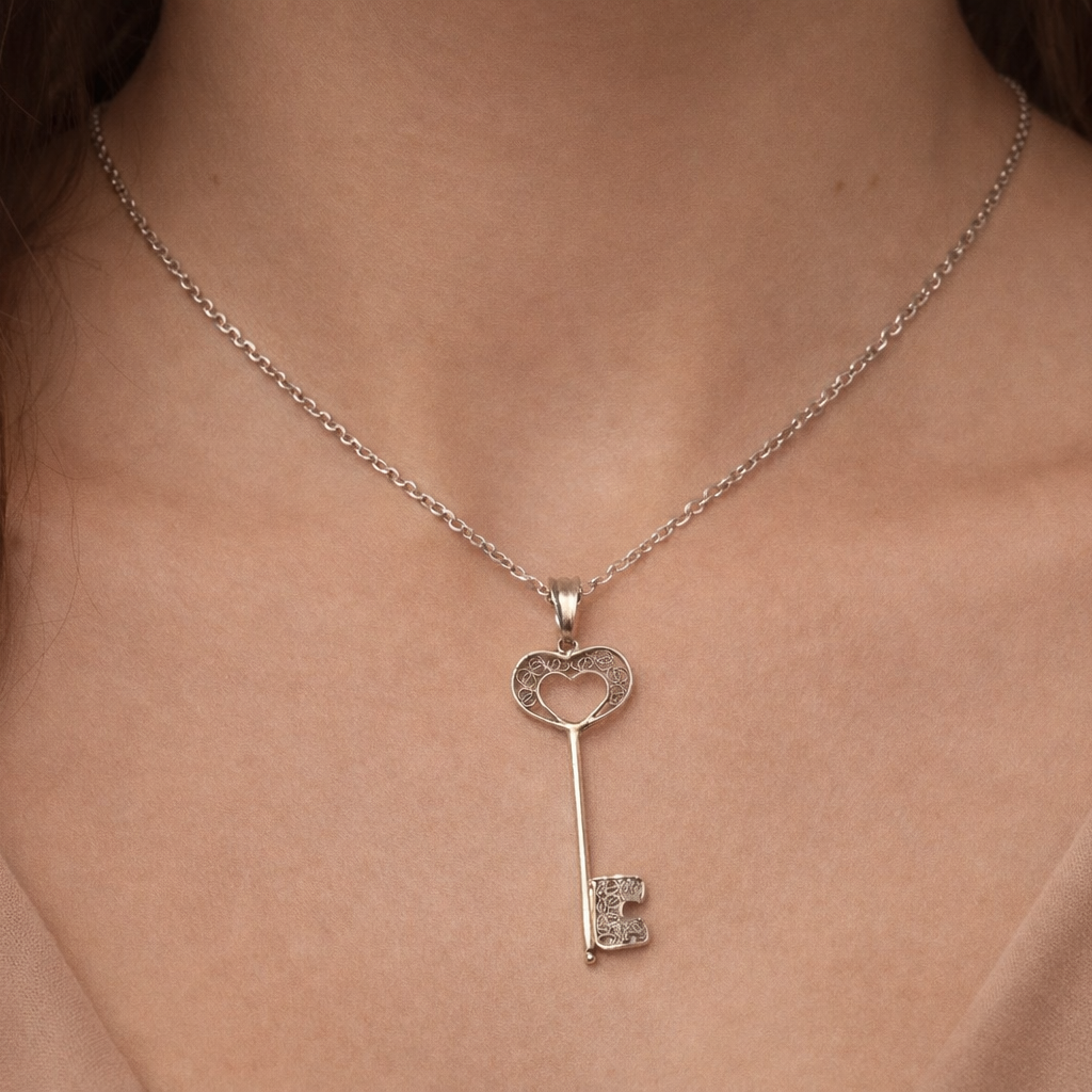 Silver key-shaped pendant necklace on a person's neck